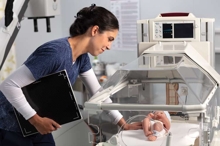 Manufacturer reference photograph showing a DRX Plus 2530C detector held beside an incubator; surrounding equipment is not the supplied package