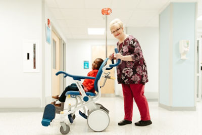 Patient seated in a Stryker Prime TC hospital transport chair, manufacturer product image