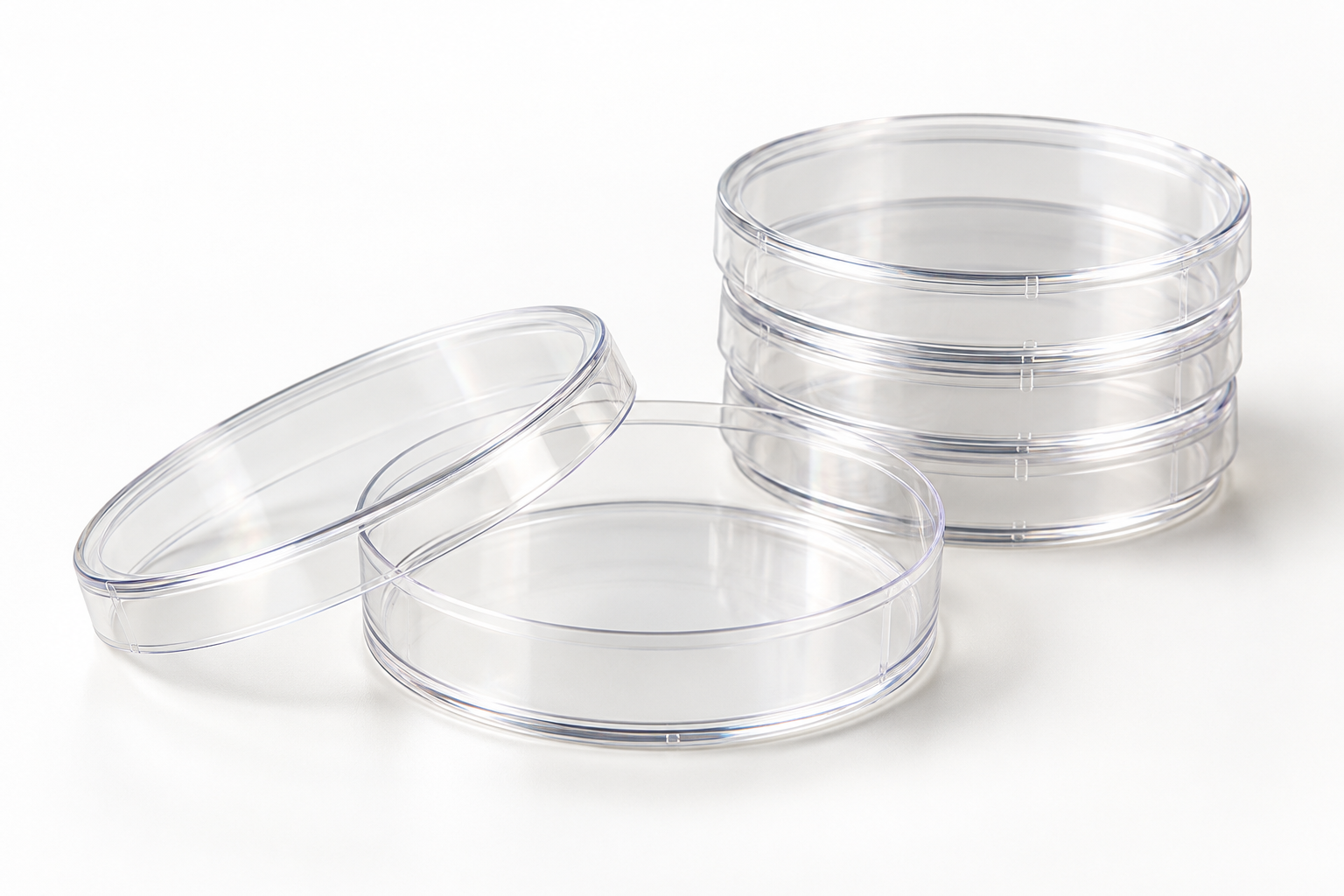 Clear 35 mm cell culture dish with transparent lid beside a small stack
